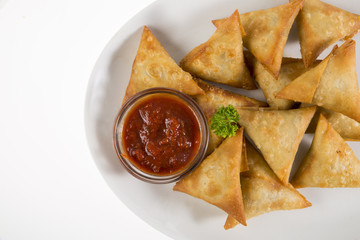 Cape Malay Samoosas on white plate served with Atjar sauce.