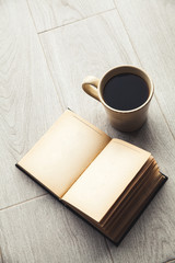 Large cup of coffee and open book. Education, hobby, drink.