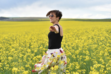 Fototapeta premium Happy woman cheering in canola field in the summer