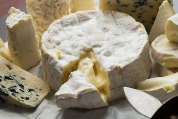 Cheese assorted on a table background. Variety sorts for appetizing, gourmet, delicious snacks. Traditional French dish for wine on lunch and dinner closeup. Camembert, Roquefort.