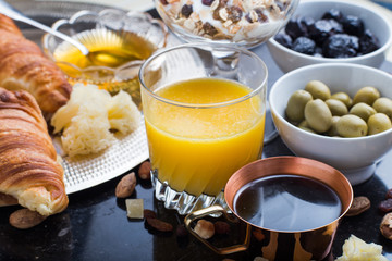 Breakfast assorted yoghurt, granola, coffee, juice, croissant, olives. Appetizer mix with morning dishes. Healthy, fresh, delicious food on dark background. Top view. Copy space.