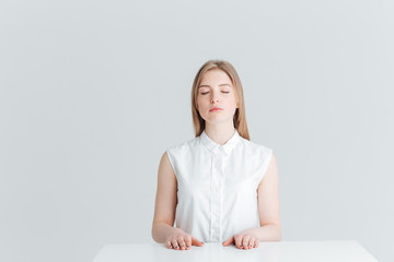 Relaxed woman with closed eyes sitting at the table