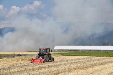Fototapeta premium Field burning of smoke and tractor