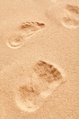 Fototapeta na wymiar Close up on a bare footprint in granular sand