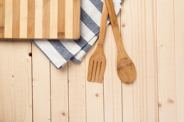 Wooden spoons and other cooking tools with blue napkins on the kitchen table.