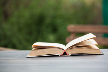 Opened book on table in garden. Outdoor. Summer. Selective focus.