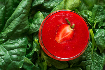 Healthy fresh strawberry smoothie on spinach leaves