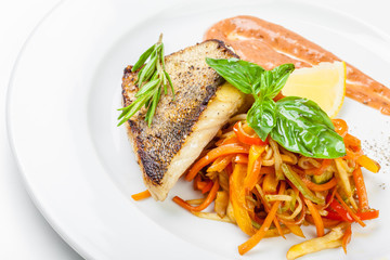 Dish of fish fillet with basil and lemon on plate isolated on white