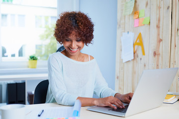 Attractive young woman working at desk with her laptop and docum