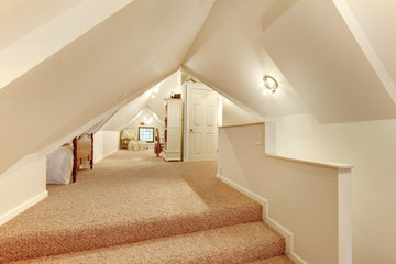 Lovely beige attic bedroom with vaulted ceiling and carpet floor