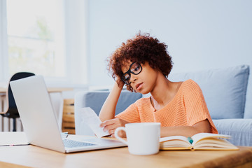 young woman looking stressed while looking at bills