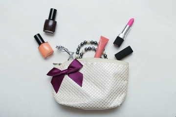 make up bag with cosmetics and brushes on wooden background