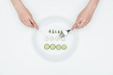 Hands of young woman eating cucumber, mozzarella and herbs