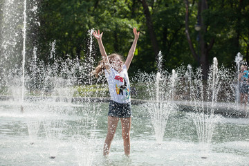 Enjoy fountain, young girl bathes in a city fountain
