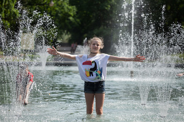 Enjoy fountain, young girl bathes in a city fountain
