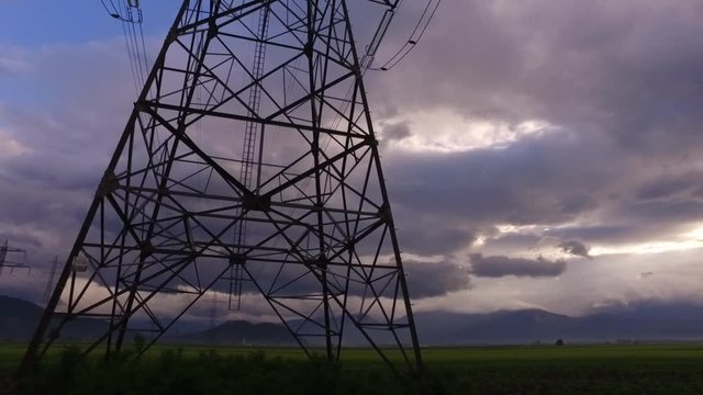 Electric masts on the fields and intensive clouds above.