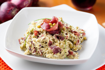 Risotto con bresaola e piselli nel piatto di ceramica bianca sulla tavola apparecchiata
