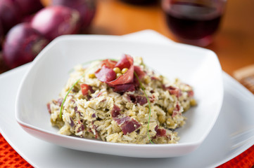 Risotto con bresaola e piselli nel piatto di ceramica bianca sulla tavola apparecchiata