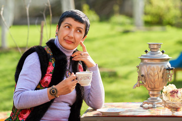 Русская женщина пьет чай из самовара в саду
