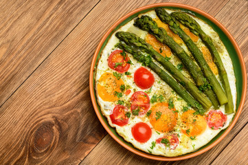 Fried eggs with green asparagus and tomatoes.
