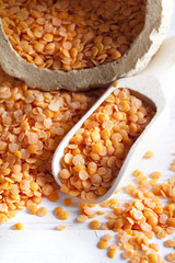 Red lentils on white wood background