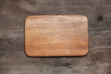 Wooden cutting board on old wooden table.Top view.