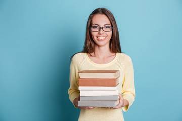 Girl holding many books over blue background