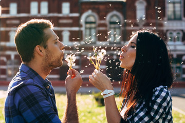 man and woman blowing dandelions on each other