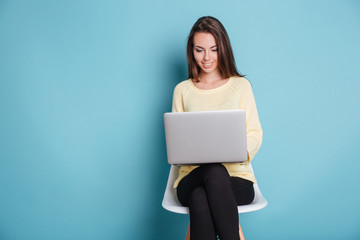 Smart beautiful young girl using laptop over blue background