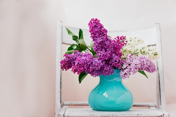 Still life with lilac flowers in vase turquoise placed on a wooden shabby background