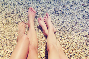 Female and children's feet on a beach against the sea in a summer sunny day. Family holiday. Family rest