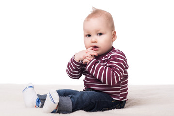 Fototapeta premium cute baby boy sitting on a blanket and looking at camera. child on a white background. happy family concept