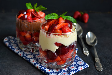 dessert with strawberries and cream in a glass on a black backgr