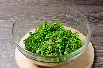 Full bowl of fresh green salad, tomatoes, cucumber close up on a wood table against a dark background on a rustic kitchen. Top view.