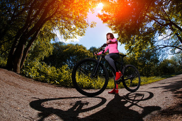 Fototapeta premium Young woman having fun riding a bicycle in the park.