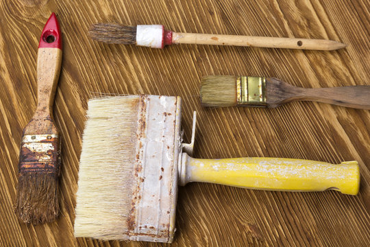 Old dirty vintage paint brushes on grunge wooden background