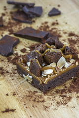 One piece of brownie with chocolate and cocoa on the light wooden background