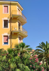 Fototapeta premium immeuble avec balcons et jardin exotique sous ciel bleu