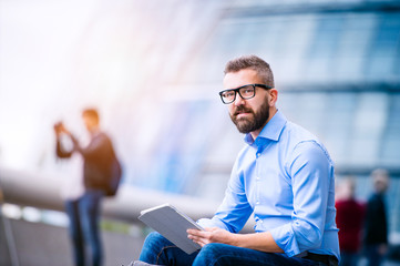 Manager with tablet, sitting on stairs, London, City Hall