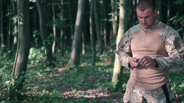 Military sharpen knife with bilestone in the forest. Slow motion