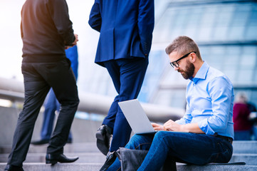Manager with laptop, sitting on stairs, London, City Hall