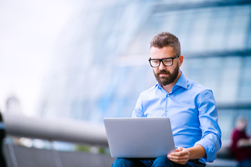Manager with laptop, sitting on stairs, London, City Hall