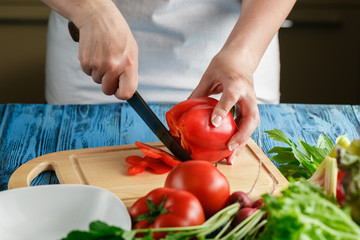 cooking and home concept - close up of female hand cutting tomat