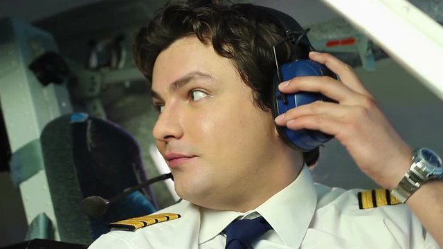 Male pilot talking to crewmember, coordinating actions during flight, teamwork