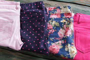Blue floral pattern pants. Folded bright pink trousers. Woman's pants in outlet store. Newly purchased clothing on shelf.