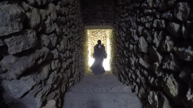 Knight girl in a flowing cloak is the catacombs of an ancient castle