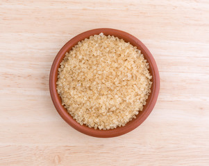 Turbinado sugar in bowl on a wood table top.