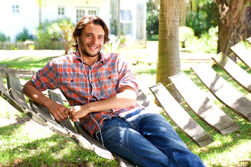 Obraz premium Young man lying in hammock with earphones