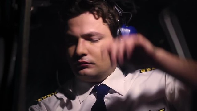 Overworked plane crewmember checking cockpit panel, tired after long flight