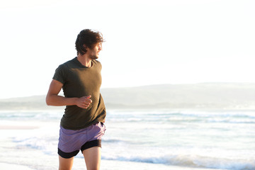 Handsome young man running by the ocean